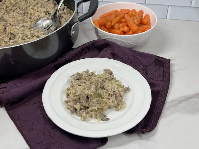 A steaming skillet filled with seasoned ground beef, tender rice, and mushrooms, bell pepper, onion, garlic and seasonings.