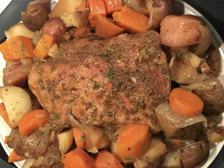 A juicy, slow-cooked pork loin roast surrounded by tender carrots, potatoes, and onions in a crock-pot.