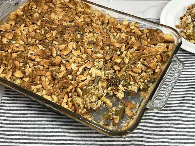 A golden, crispy-topped chicken green bean casserole in a baking dish, with melted cheese, crunchy stuffing and fried onions.