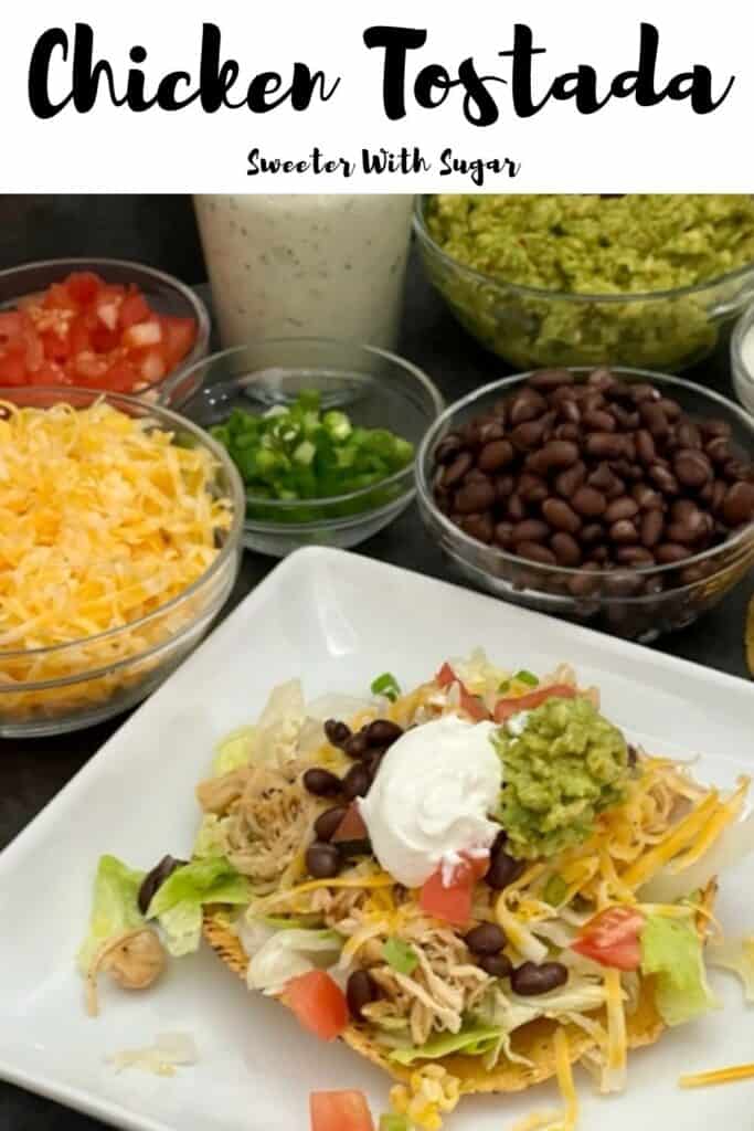 Chicken Tostada is a delicious dinner recipe with tender chicken, crisp lettuce, crunchy tostadas, guacamole, sour cream, lettuce, tomatoes, black beans, cheese and a creamy dressing. #ChickenDinner #SlowCooker #Guacamole #CilantroLimeDressing #TacoSalad #Chicken #Cheese 