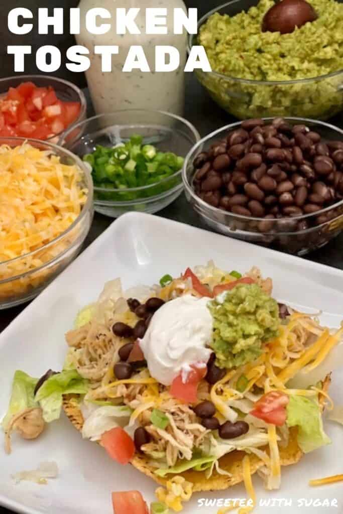 Chicken Tostada is a delicious dinner recipe with tender chicken, crisp lettuce, crunchy tostadas, guacamole, sour cream, lettuce, tomatoes, black beans, cheese and a creamy dressing. #ChickenDinner #SlowCooker #Guacamole #CilantroLimeDressing #TacoSalad #Chicken #Cheese 