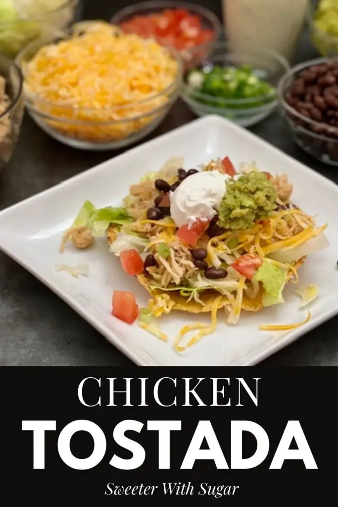 Chicken Tostada is a delicious dinner recipe with tender chicken, crisp lettuce, crunchy tostadas, guacamole, sour cream, lettuce, tomatoes, black beans, cheese and a creamy dressing. #ChickenDinner #SlowCooker #Guacamole #CilantroLimeDressing #TacoSalad #Chicken #Cheese 