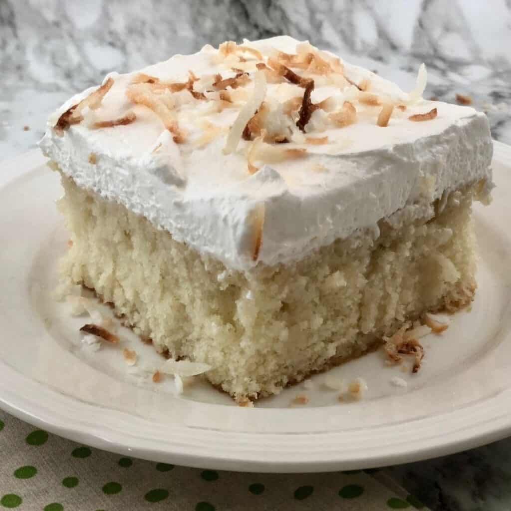 Toasted Coconut Cake is a light and delicious dessert made with a cake mix, Cool Whip and coconut. You can use toasted coconut or just coconut cream. #Desserts #Cakes #Coconut #CreamOfCoconut #WhiteCake #HolidayDesserts #EasyCakeRecipe