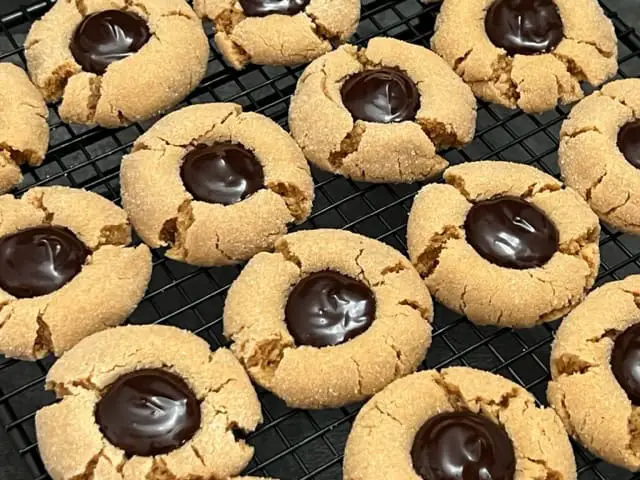 Chocolate Peanut Butter Thumbprint Cookies are cute and delicious! The soft peanut butter cookie is rolled in sugar and the middle is filled with a chocolate filling you will love! #ChocolateGanache #PeanutButterCookies #ChocolatePeanutButterCookies #ThumbprintCookies #PeanutButterBlossoms