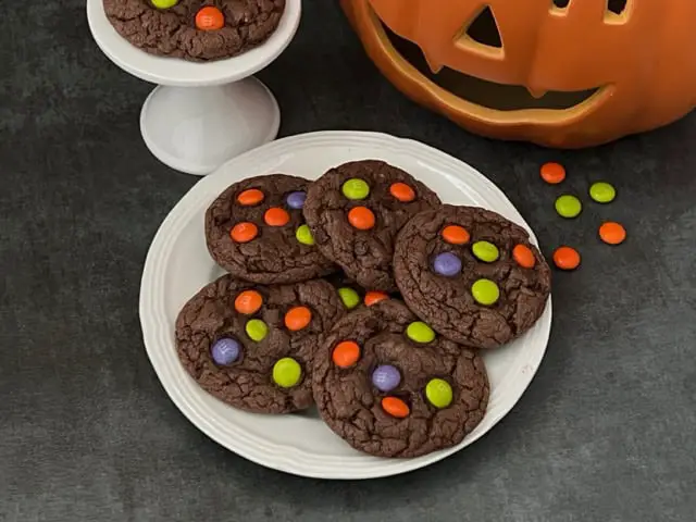 Halloween M & M Cookies are super easy to make. They are a yummy soft chocolate cookie topped with M & M's Ghoul Mix plain M & M's. They are perfect for Halloween. #Cookies #M&Ms #ChocolateCookies #CakeMixCookies #M&MsGhoulMix #EasyCookieRecipe