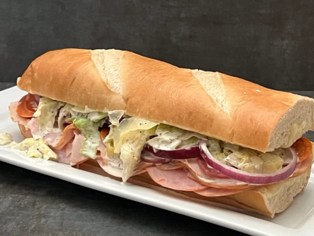 Italian Sub Sandwich is filled with four different deli meats, cheese, veggies and a delicious dressing. It is quick to make and delicious! #Subs #Sandwiches #DeliSandwiches #SubmarineSandwiches #ItalianGrinderSandwiches #Lunches #SandwichRecipes