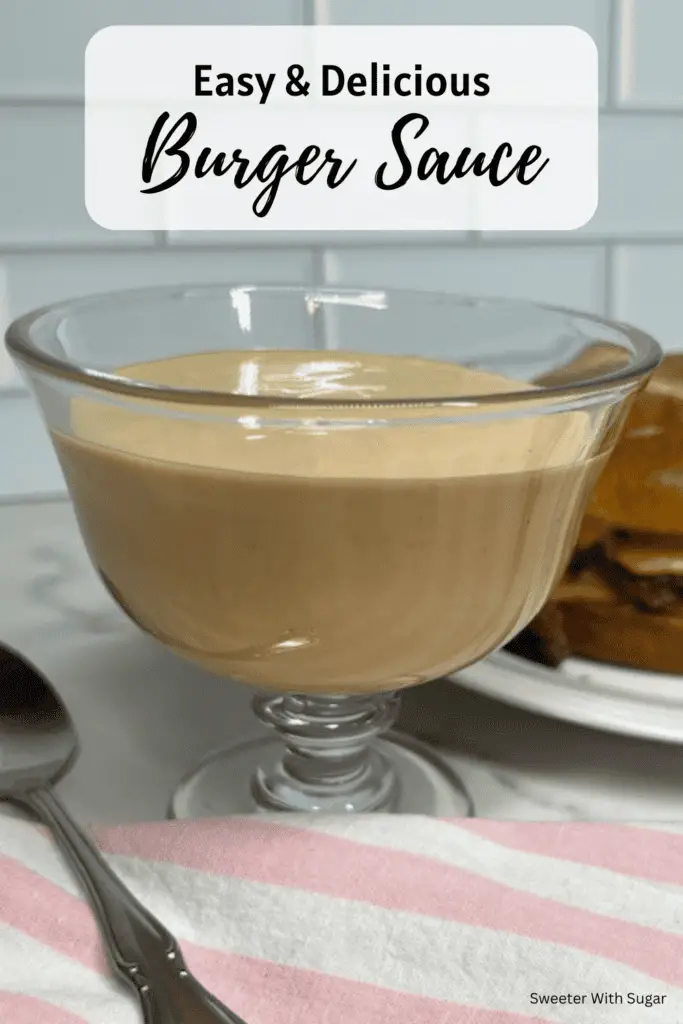 A small bowl of creamy homemade burger sauce with a spoon, surrounded by burger ingredients like lettuce, tomato, and pickles. #BurgerSauce #HomemadeSauce #EasyRecipe #SecretSauce #BurgerLover #SauceRecipe #GrillSeason