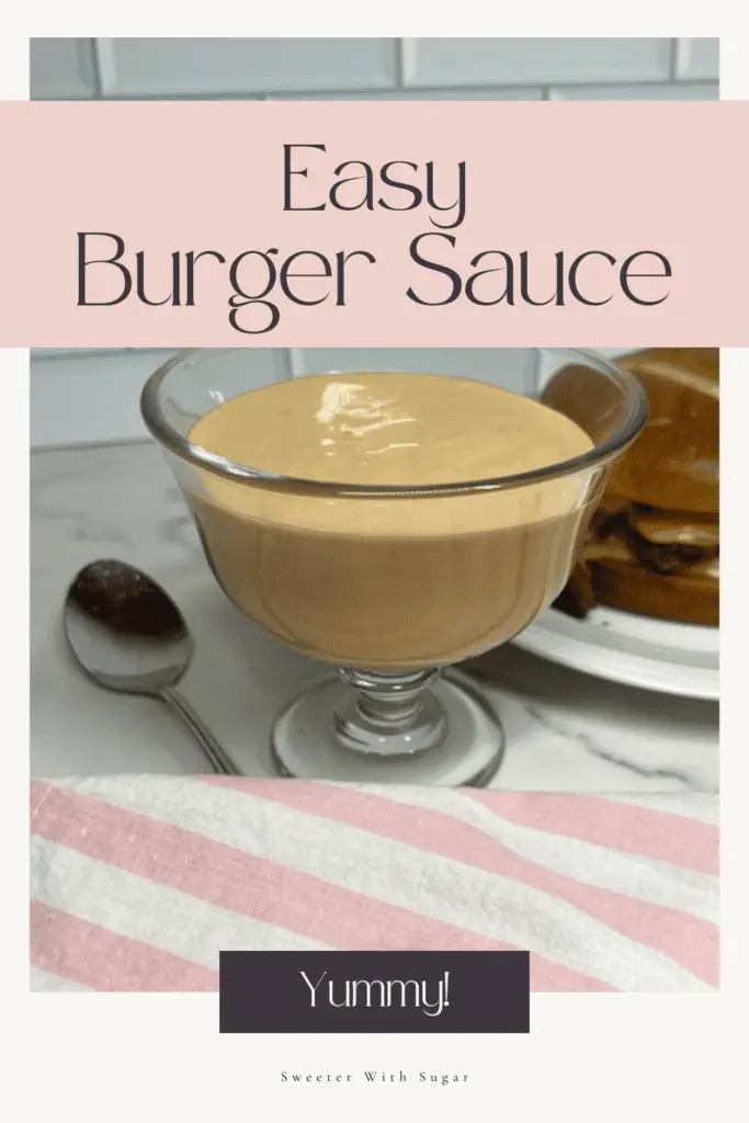 A small bowl of creamy homemade burger sauce with a spoon, surrounded by burger ingredients like lettuce, tomato, and pickles. #BurgerSauce #HomemadeSauce #EasyRecipe #SecretSauce #BurgerLover #SauceRecipe #GrillSeason