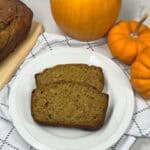 A moist and fluffy loaf of pumpkin banana bread sliced on a wooden cutting board, showing its golden-brown texture with hints of banana and spices.