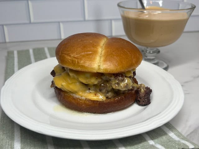 A juicy butter burger with a golden, toasted bun, melted cheese, and crispy lettuce, served with fries.