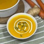 Bright orange carrot ginger soup with sour cream and pumpkin seeds.