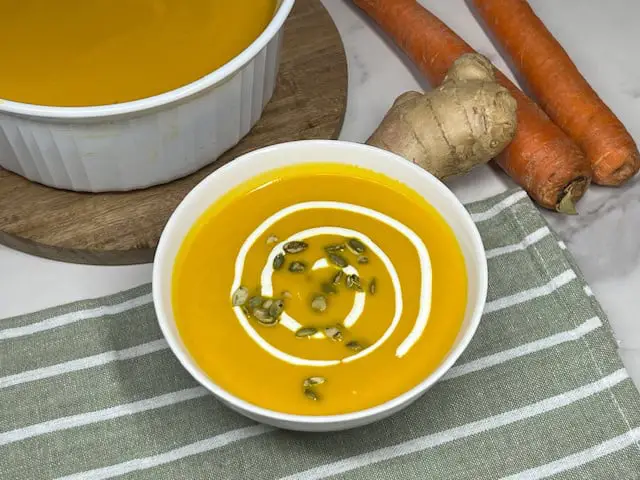 Bright orange carrot ginger soup with sour cream and pumpkin seeds.