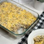 Casserole dish filled with bubbly cheesy chicken and artichoke bake fresh out of the oven